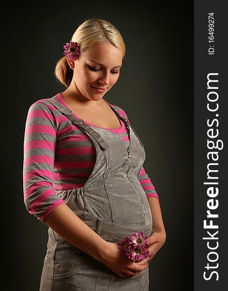 Pregnant young woman on dark background