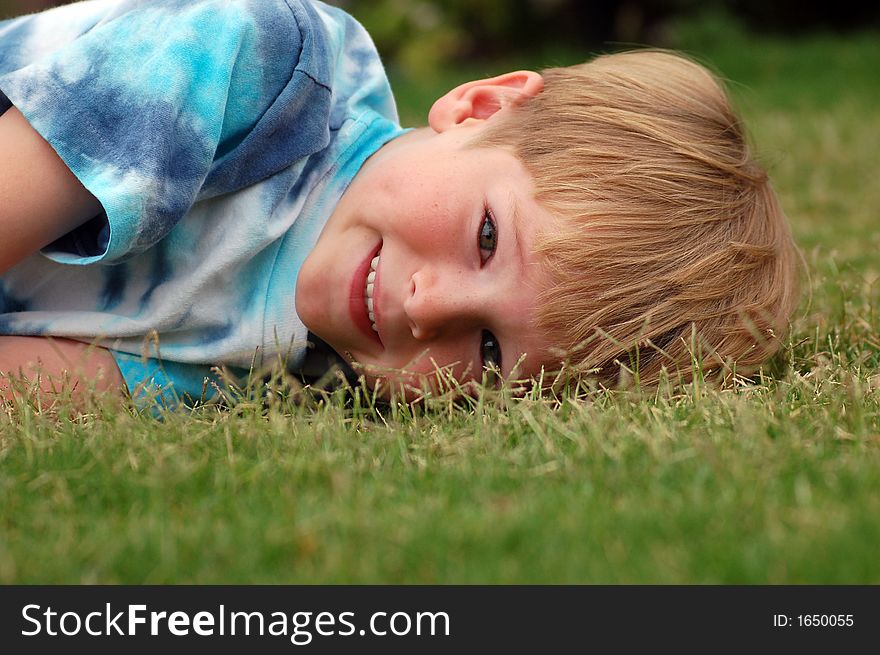 A six year old boy lying down in the grass. A six year old boy lying down in the grass.