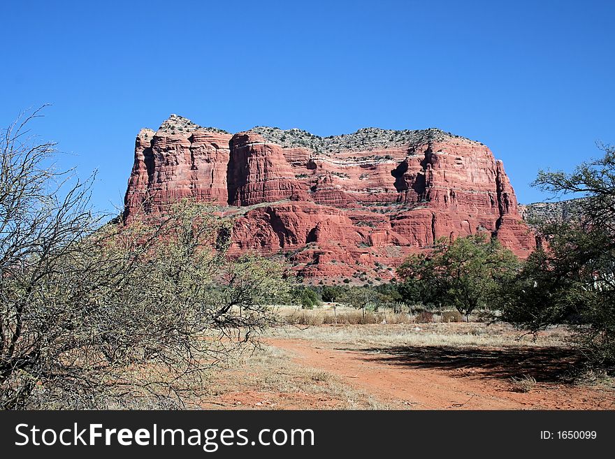 A red rock mountain in Sedona Arizona in the fall. Blue skies, lots of reds blues, yellows and greens. A red rock mountain in Sedona Arizona in the fall. Blue skies, lots of reds blues, yellows and greens