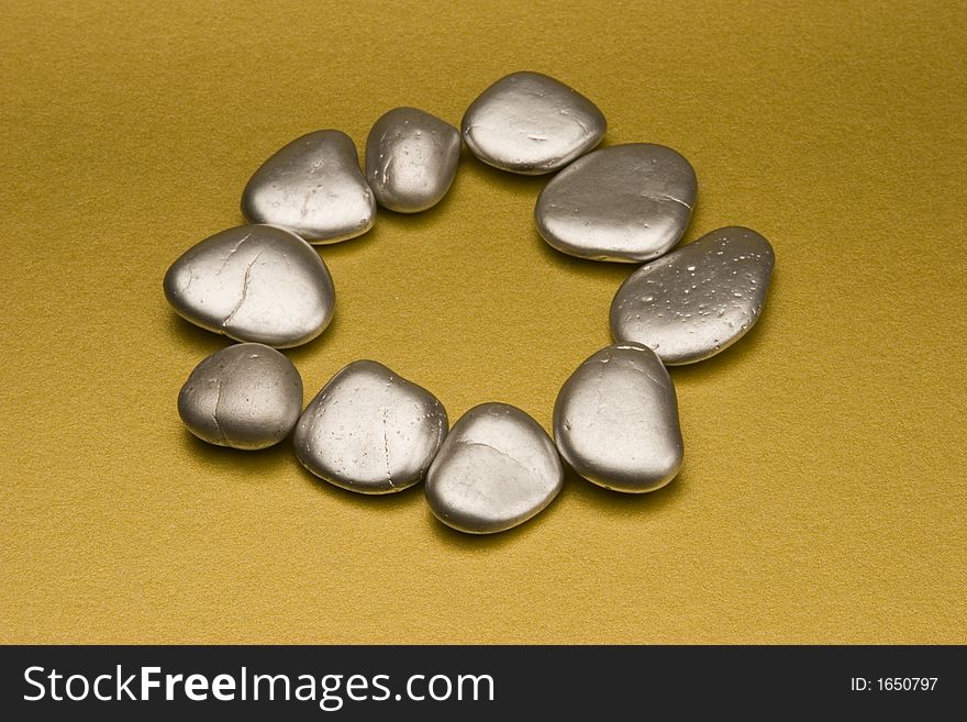 Silver painted stones set against a gold background.