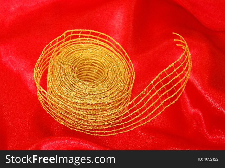 Golden christmas ribbon over red silk fabric