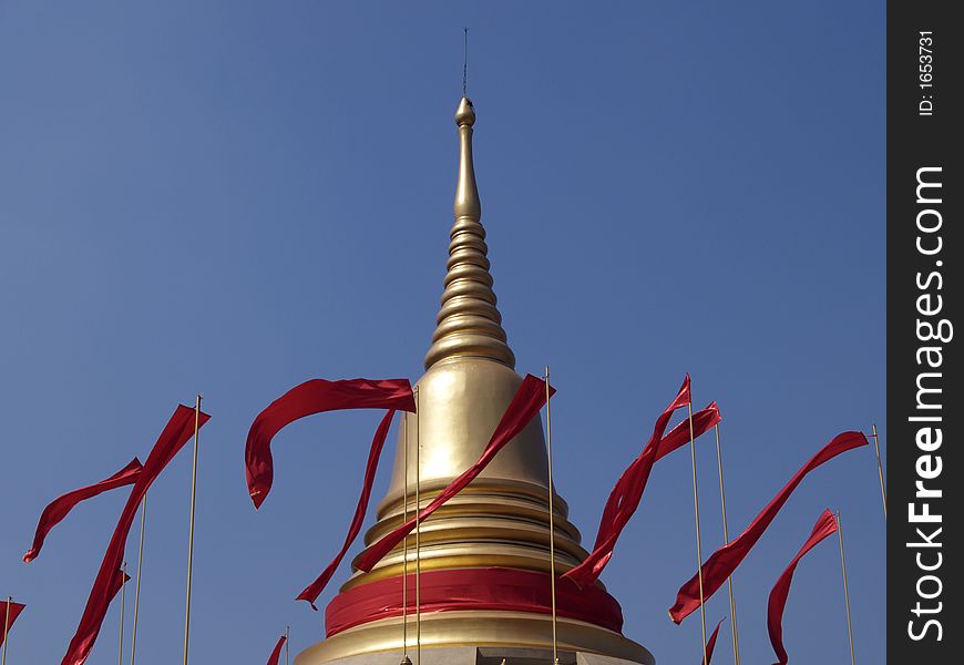 Golden cheddi with red flags at Buddhist temple in Thailand. Golden cheddi with red flags at Buddhist temple in Thailand
