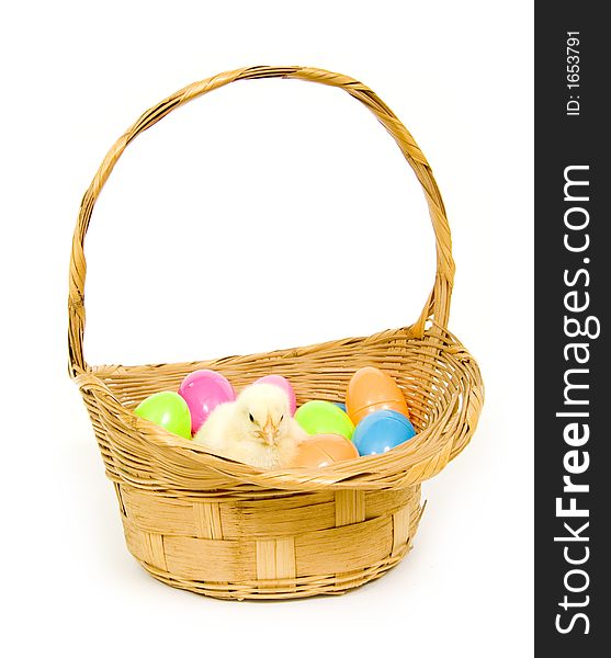 A baby yellow chick sits in a basket with a collection of colorful Easter eggs. A baby yellow chick sits in a basket with a collection of colorful Easter eggs.
