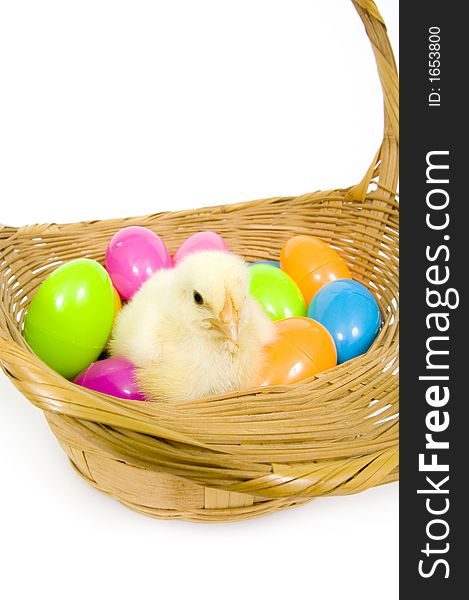 A baby yellow chick sits in a basket with a collection of colorful Easter eggs. A baby yellow chick sits in a basket with a collection of colorful Easter eggs.