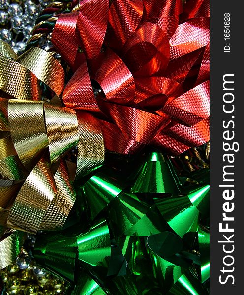 Red, gold, and green holiday bows on top of gold and silver beads