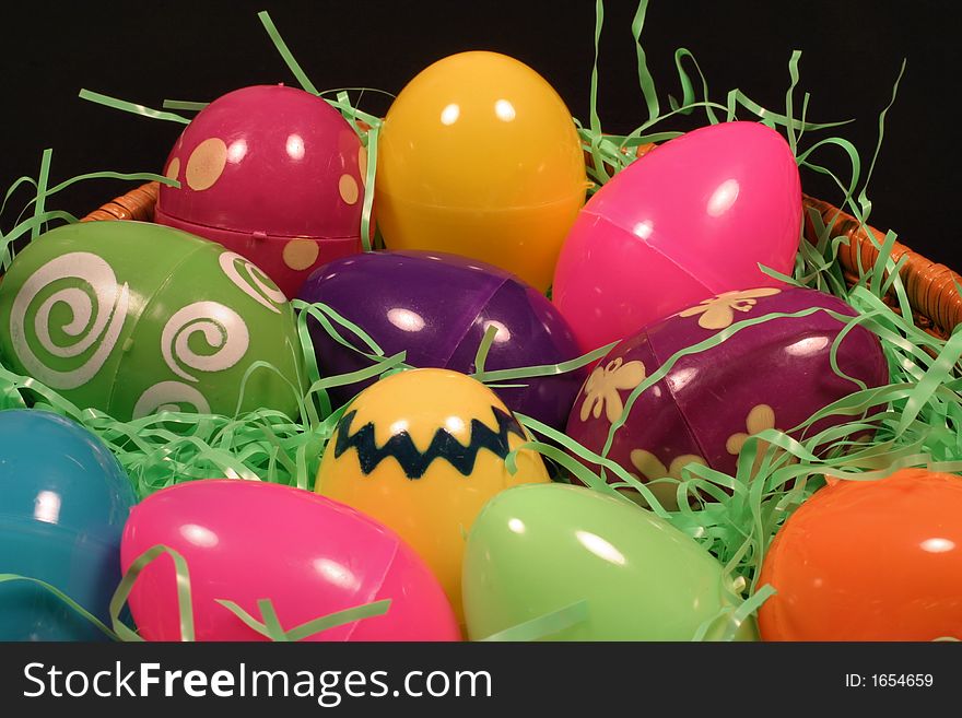 A basket of colored plastic Easter eggs with green shred filler and a dark background.