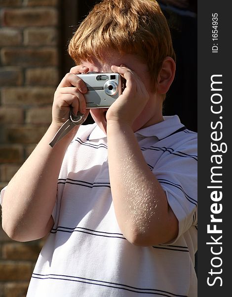 Young boy taking a photograph with his first digital camera. Young boy taking a photograph with his first digital camera