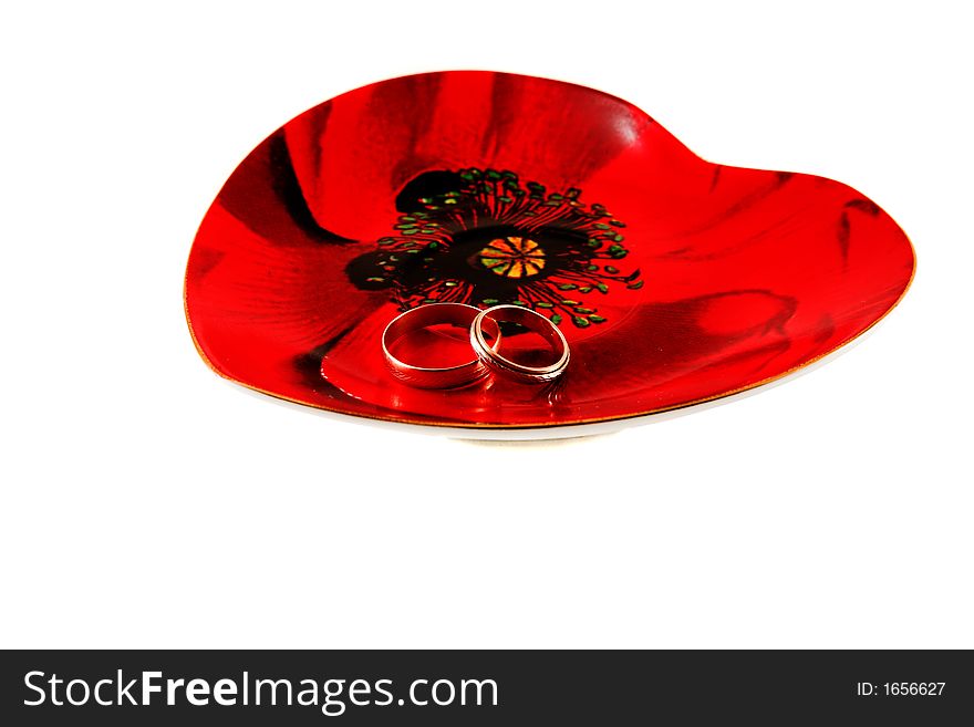 Two wedding rings on the heart-shaped plate isolated. Two wedding rings on the heart-shaped plate isolated