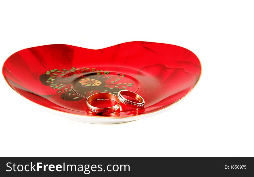 Two wedding rings on the heart-shaped plate isolated. Two wedding rings on the heart-shaped plate isolated