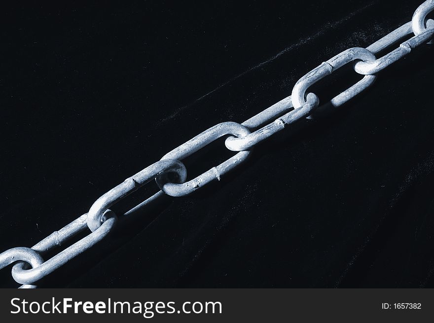 Long heavy chain, silver-colored against black-velvet, going diagonally over image. Long heavy chain, silver-colored against black-velvet, going diagonally over image