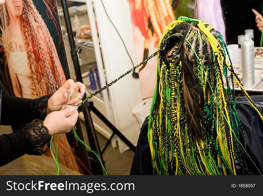 Woman coiffure. Hairdresser does hairstyle from pigtail.