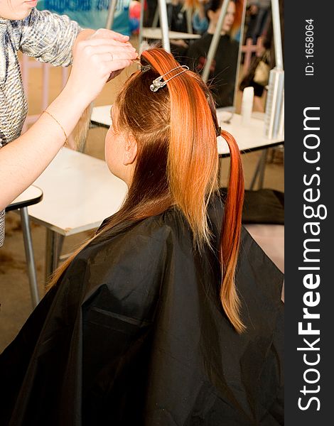 Woman coiffure. Hairdresser does young girl a hairstyle.