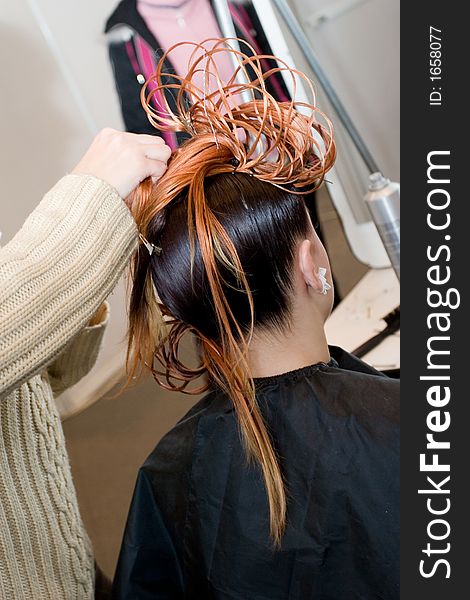 Woman coiffure. Hairdresser does young girl a hairstyle.