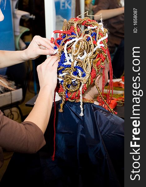 Woman coiffure. Hairdresser does hairstyle from pigtail.