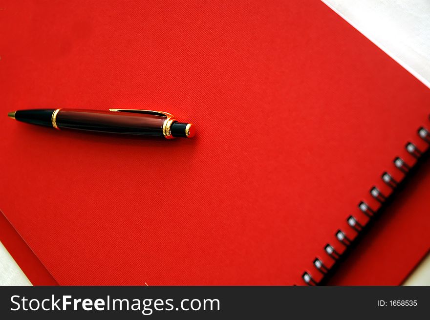 Red note book and pen on the table