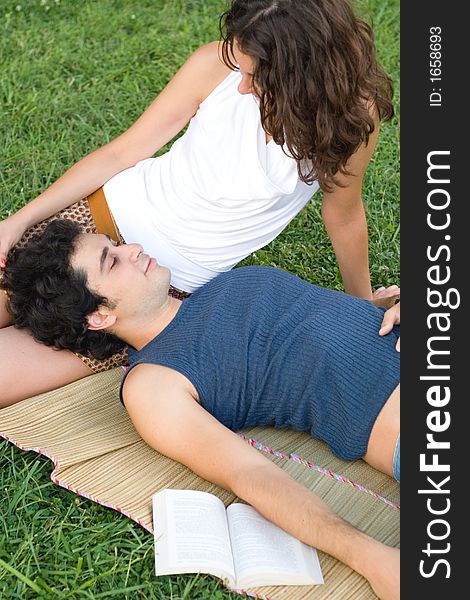 Romantic, young couple lying on the grass with a book. Romantic, young couple lying on the grass with a book