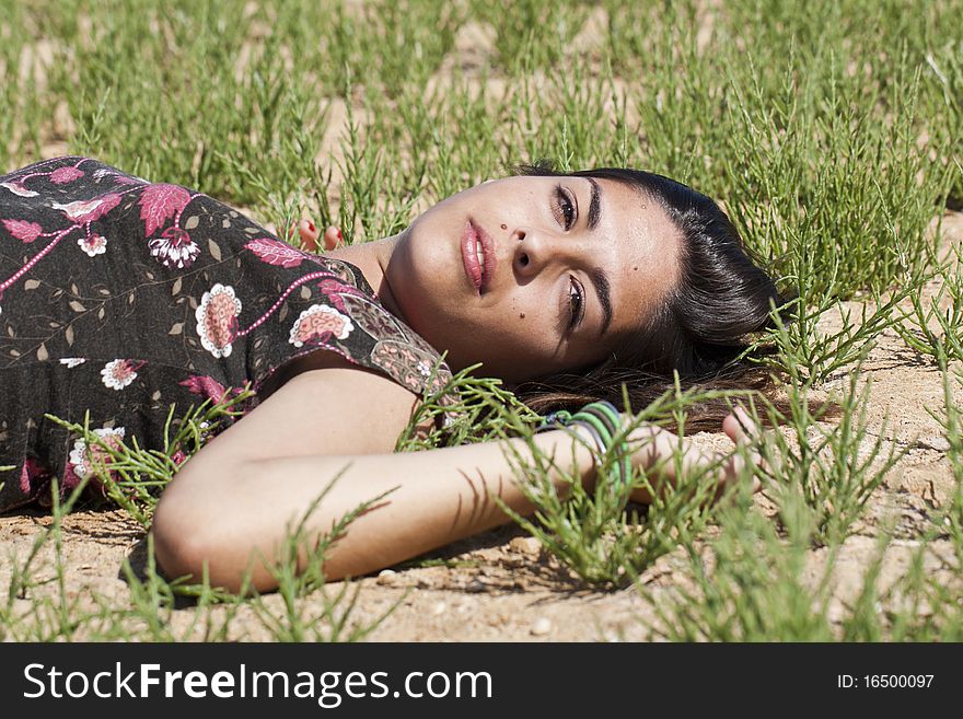 Beautiful girl with floral dress on the ground in a sunny day. Beautiful girl with floral dress on the ground in a sunny day.