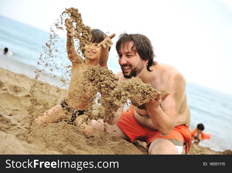 Playing together in sand on beach, young father and a little son