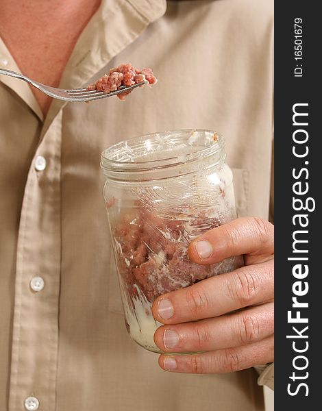 Raw Foodism. Man eating raw beef with cream and butter from glass jar.