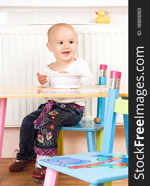 Beautiful baby girl sitting at the table