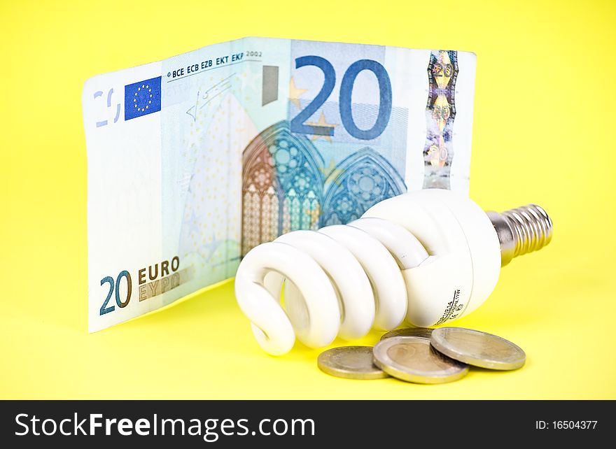 Twenty euros and economic lamp bulb on yelloy backgrounds. Twenty euros and economic lamp bulb on yelloy backgrounds