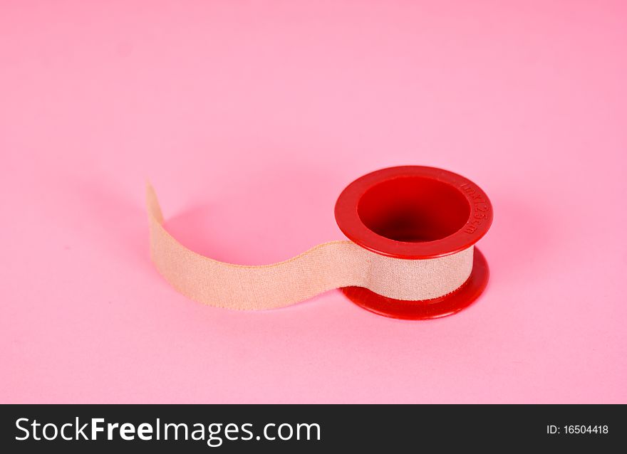 Roll of medical sticking plaster isolated on pink