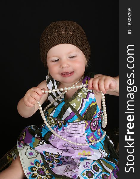 Beautiful toddler playing with a string of pearls. Beautiful toddler playing with a string of pearls