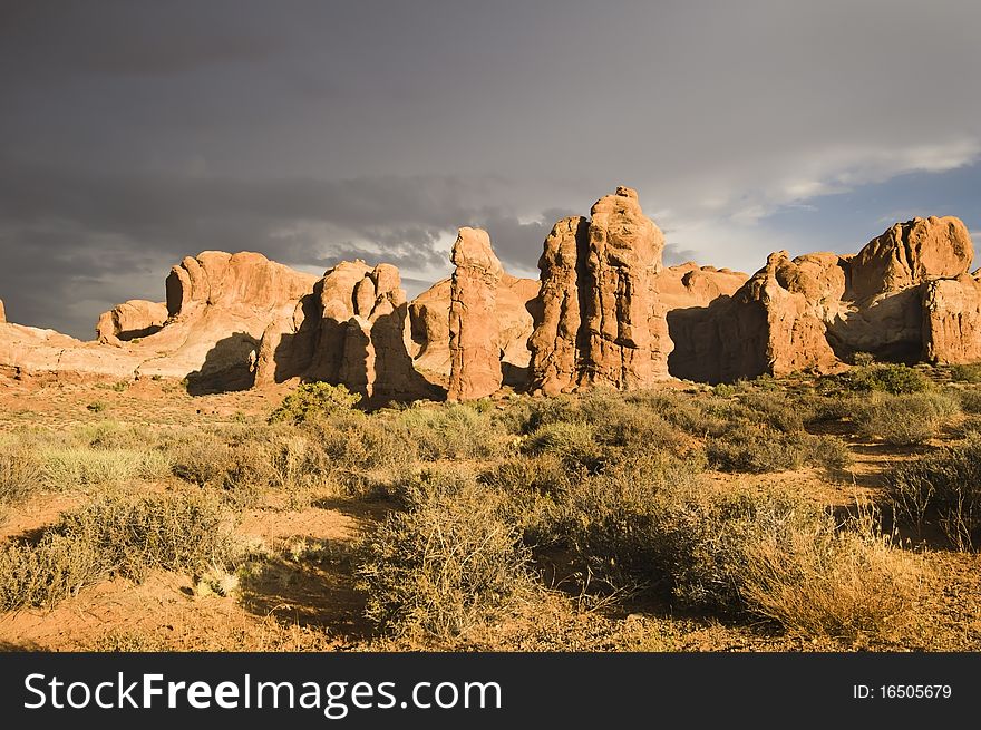 The sun breaks out over Arches National Park after a rainstorm passes over. Dark clouds in the background.