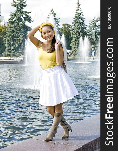 Happy girl walking near fountain in city