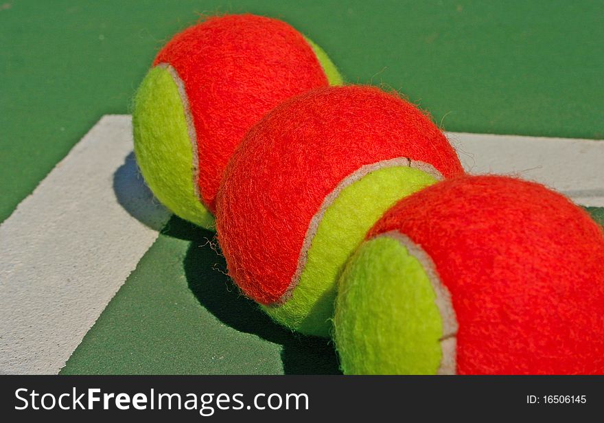 Yellow-red balls on a green tennis court. Yellow-red balls on a green tennis court