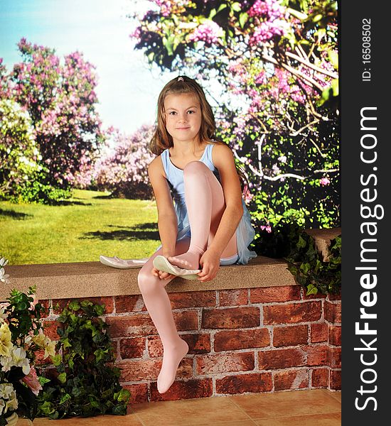 An attractive elementary girl in her ballet dress, putting on her slippers on a garden wall. An attractive elementary girl in her ballet dress, putting on her slippers on a garden wall.
