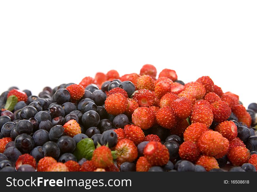 Wild strawberries and blueberries on a white background