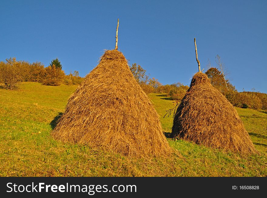 A haystacks on an autumn hillside in evening illumination. A haystacks on an autumn hillside in evening illumination.