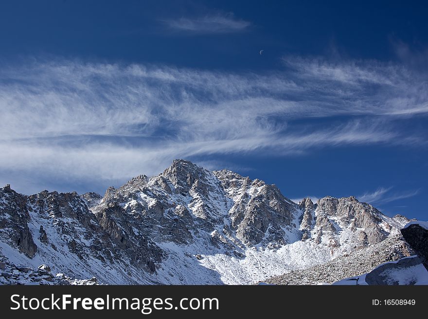 Photo of Pogranichny peak in Sayan Mountains. Moon is visible. Photo of Pogranichny peak in Sayan Mountains. Moon is visible.