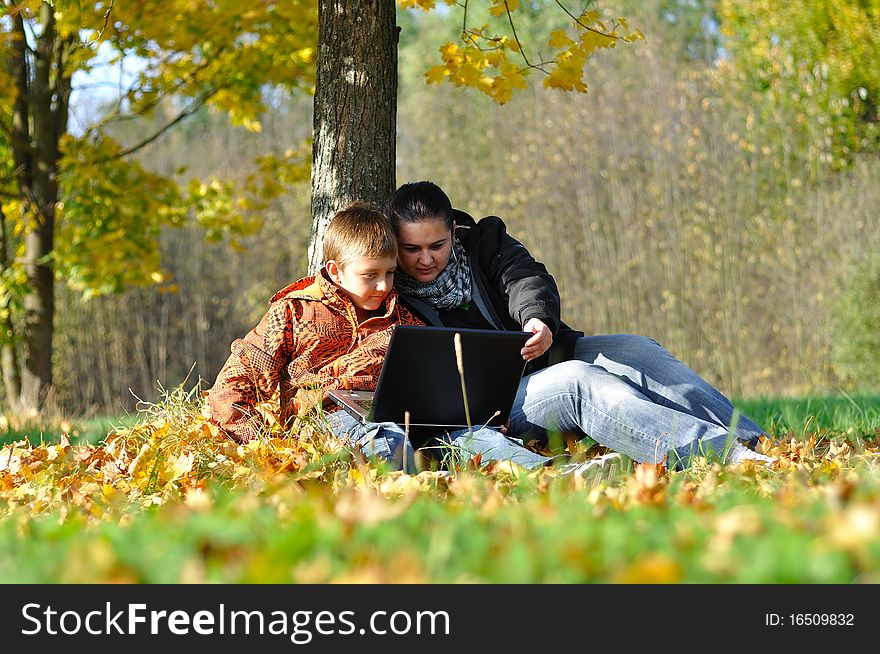 Family with laptop under tree in autumn park. Family with laptop under tree in autumn park