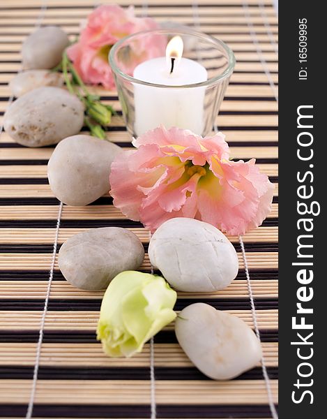 Stones and flowers with candle on bamboo mate. Stones and flowers with candle on bamboo mate