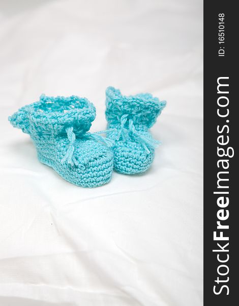 Tiny knitted baby bootees on white background. Tiny knitted baby bootees on white background