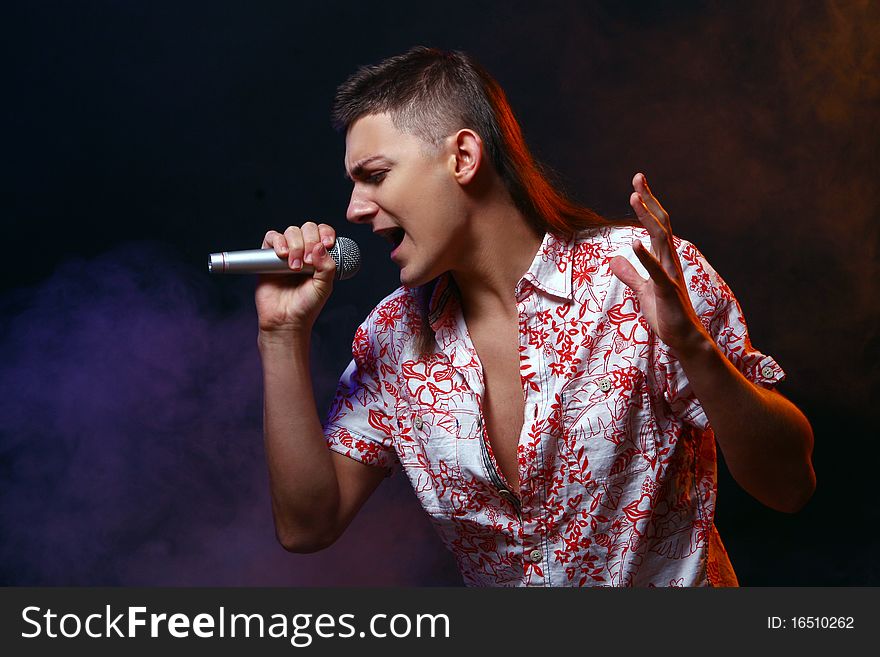 Singer with silver microphone on black background