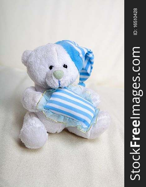 White toy teddy bear with small blue pillow and blue hat. White toy teddy bear with small blue pillow and blue hat