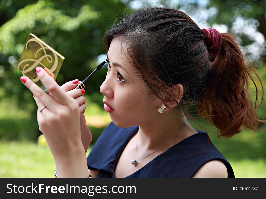 Young Woman Applying Mascara Using Lash Brush
