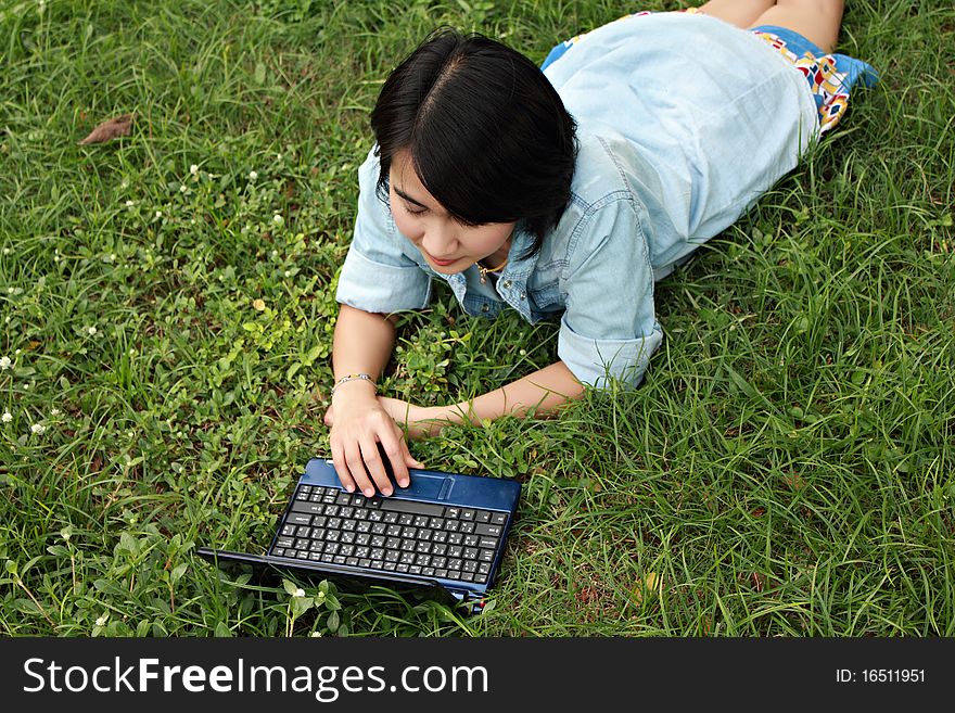 A smiling young girl with laptop outdoors in the park