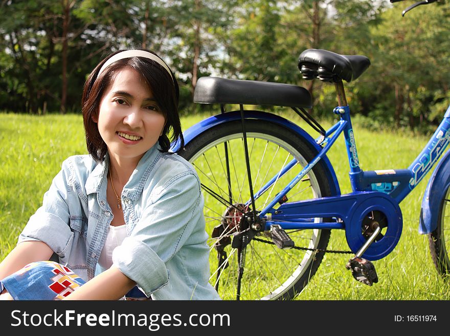 Woman with a bike outdoors smiling in the park