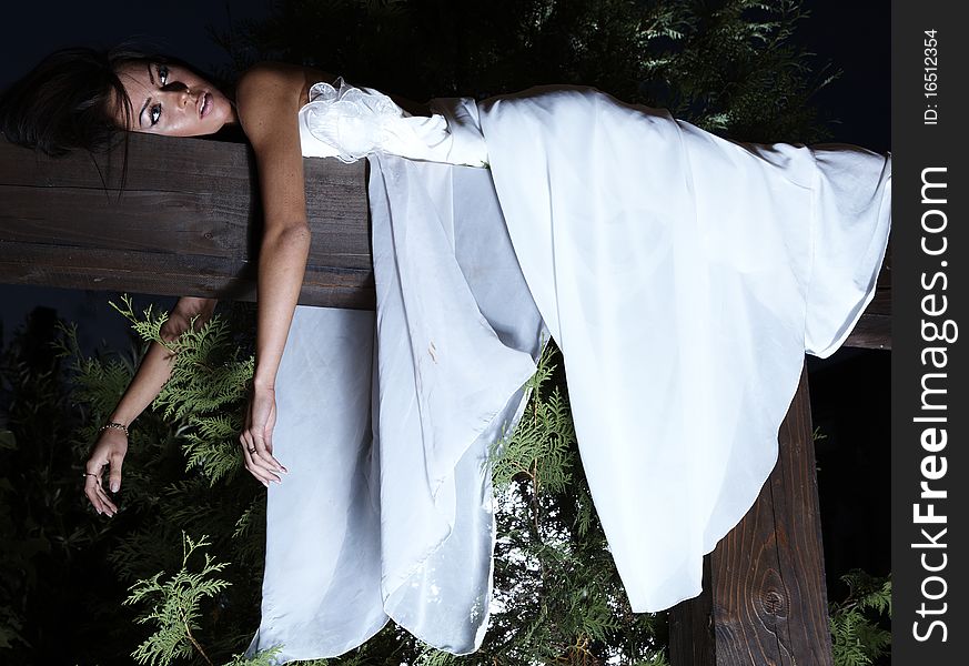 Attractive suntanned girl in white dress poses on a wooden beam. Attractive suntanned girl in white dress poses on a wooden beam.