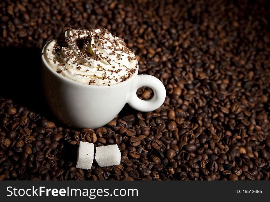 Coffee cup with cream in coffee beans. Coffee cup with cream in coffee beans