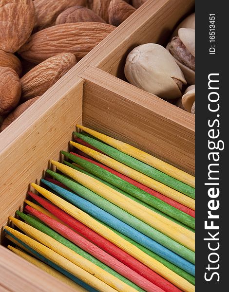 Wooden multi-coloured toothpicks for personal hygiene. Nuts as a background.