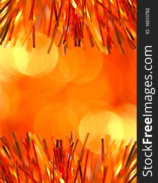Orange christmas tinsel over blurred background. Orange christmas tinsel over blurred background