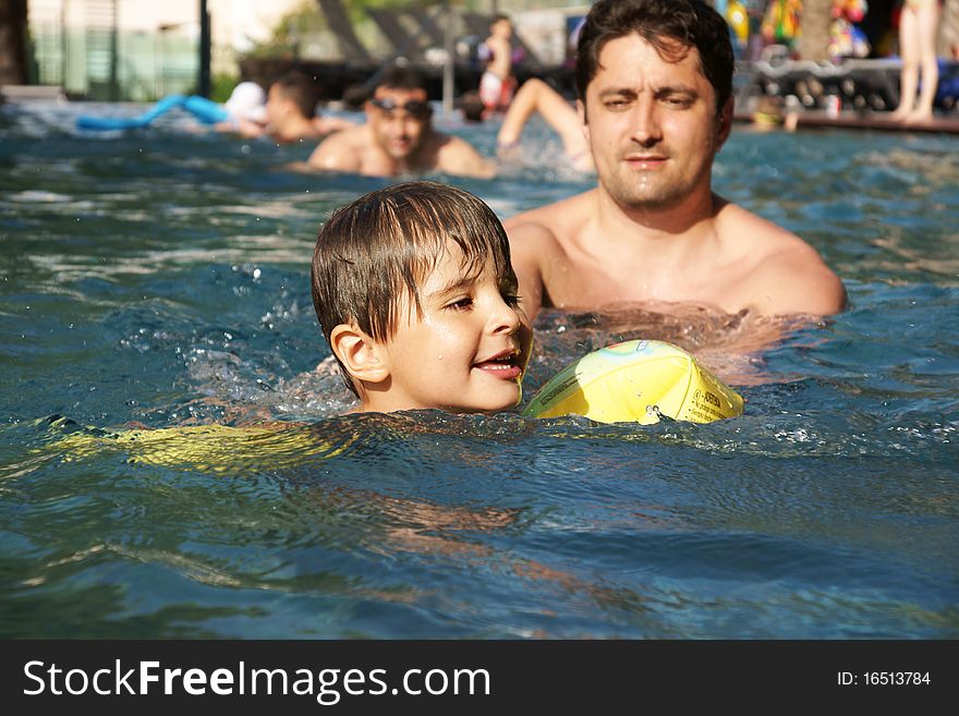 Youbg father teaching little joyful boy to swim, outdoot shot. Youbg father teaching little joyful boy to swim, outdoot shot