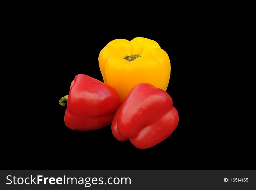 Two red and one yellow peppers on black background. Two red and one yellow peppers on black background.