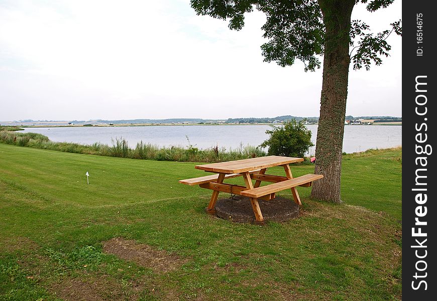 Perfect outdoors picnic setting by the sea with wooden tables. Perfect outdoors picnic setting by the sea with wooden tables