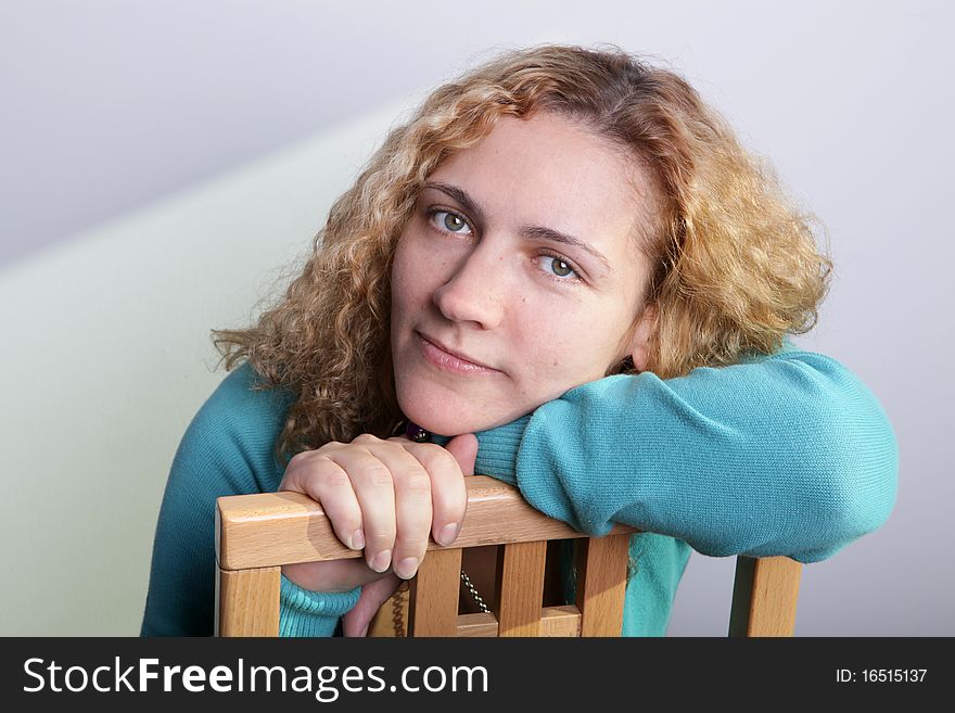 Portrait of a woman with a blond curly hair sitting on a chair. Portrait of a woman with a blond curly hair sitting on a chair